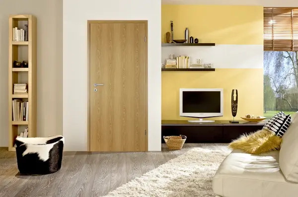 Modernes Wohnzimmer mit Holztür, Bücherregal, Fernseher und gelb-weißer Wandgestaltung.