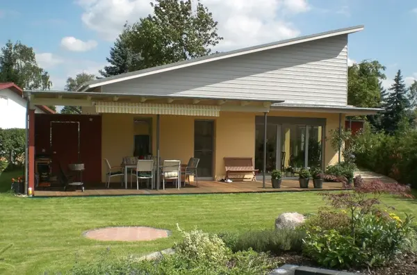 Modernes Einfamilienhaus mit großer Terrasse und gepflegtem Garten bei Sonnenschein