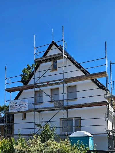 Einfamilienhaus mit Baugerüst und Bausanierung unter blauem Himmel im Sommer.